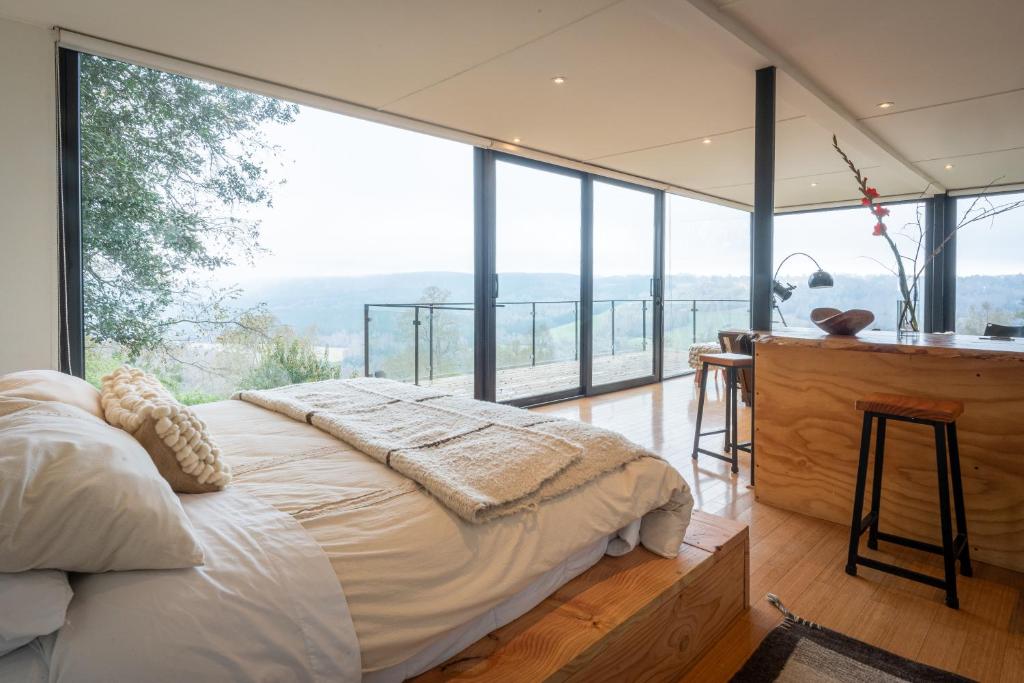 a bedroom with a bed and a desk with a view at Samadhi Eco Resort in Vilcún