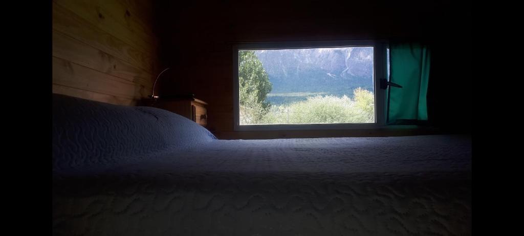 a bedroom with a bed and a window at Sur tiny house in El Bolsón