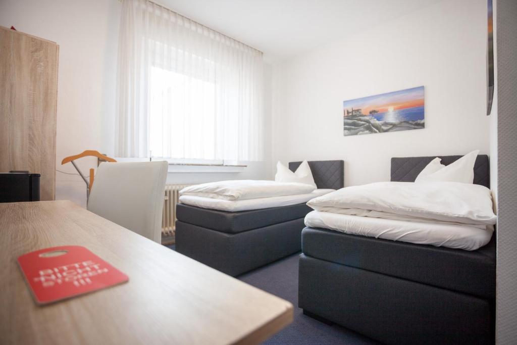 a room with two beds and a desk and a table at TM Hotel Dortmund Airport in Holzwickede