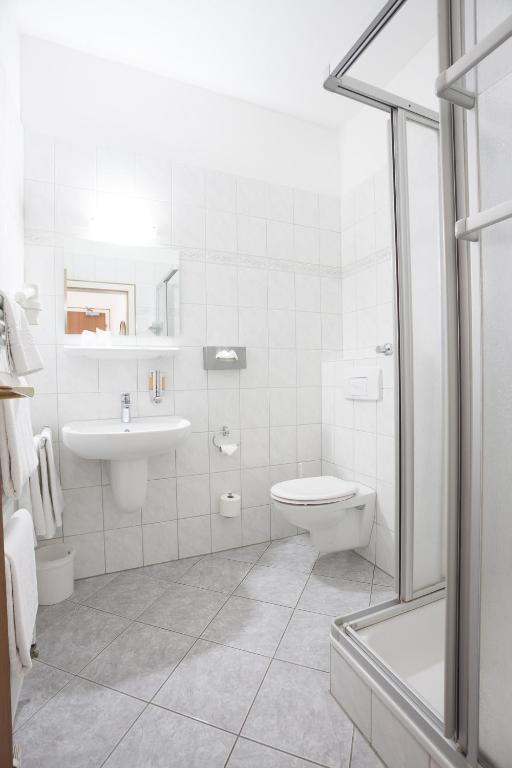 a white bathroom with a toilet and a sink at TM Hotel Dortmund Airport in Holzwickede
