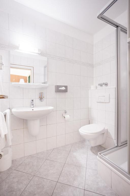 a white bathroom with a toilet and a sink at TM Hotel Dortmund Airport in Holzwickede