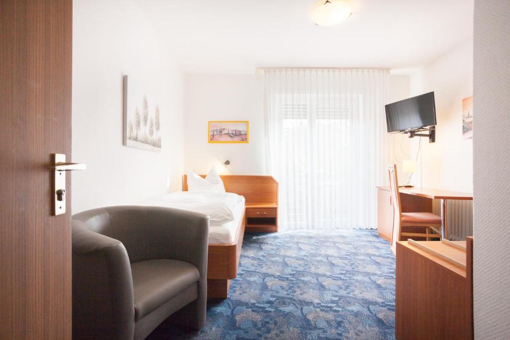 a hotel room with a bed and a chair at TM Hotel Dortmund Airport in Holzwickede
