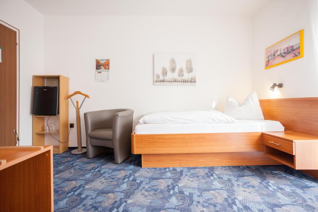 a hotel room with a bed and a chair at TM Hotel Dortmund Airport in Holzwickede