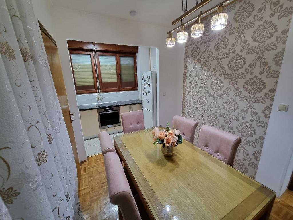 a dining room with a wooden table and pink chairs at Apartman Danijela in Vukovar