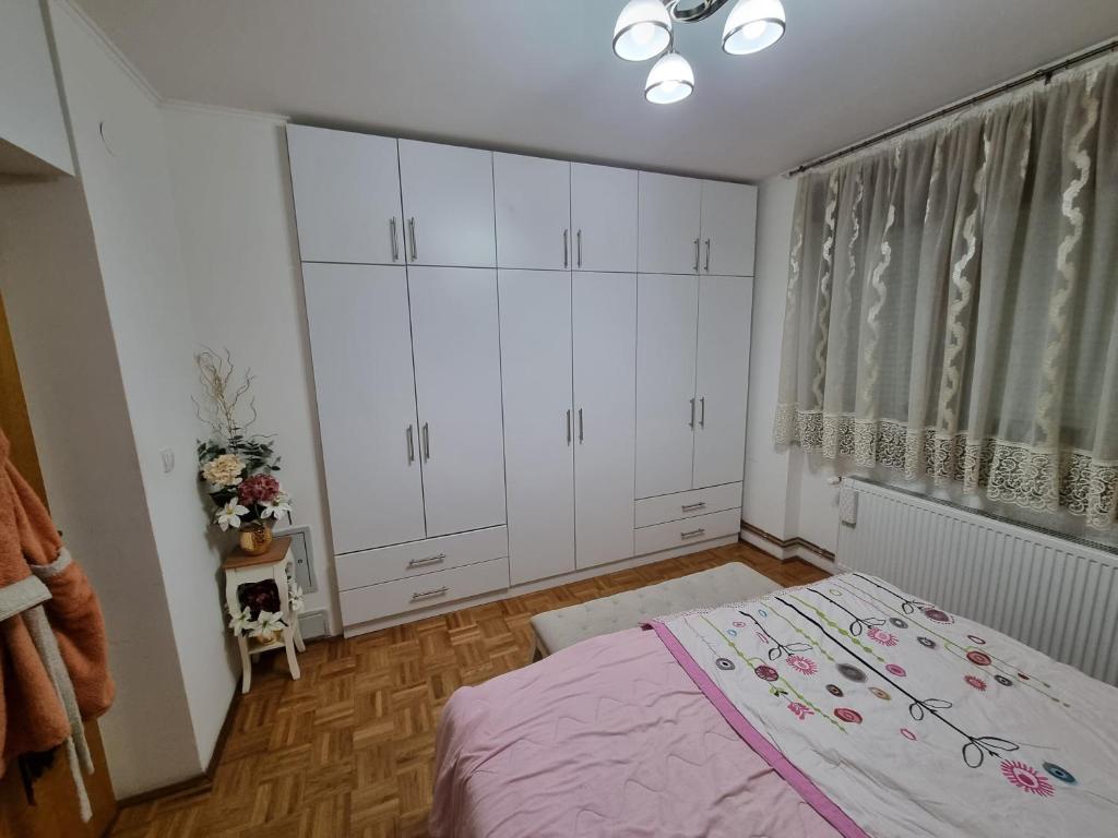 a bedroom with a bed and white cabinets and a window at Apartman Danijela in Vukovar