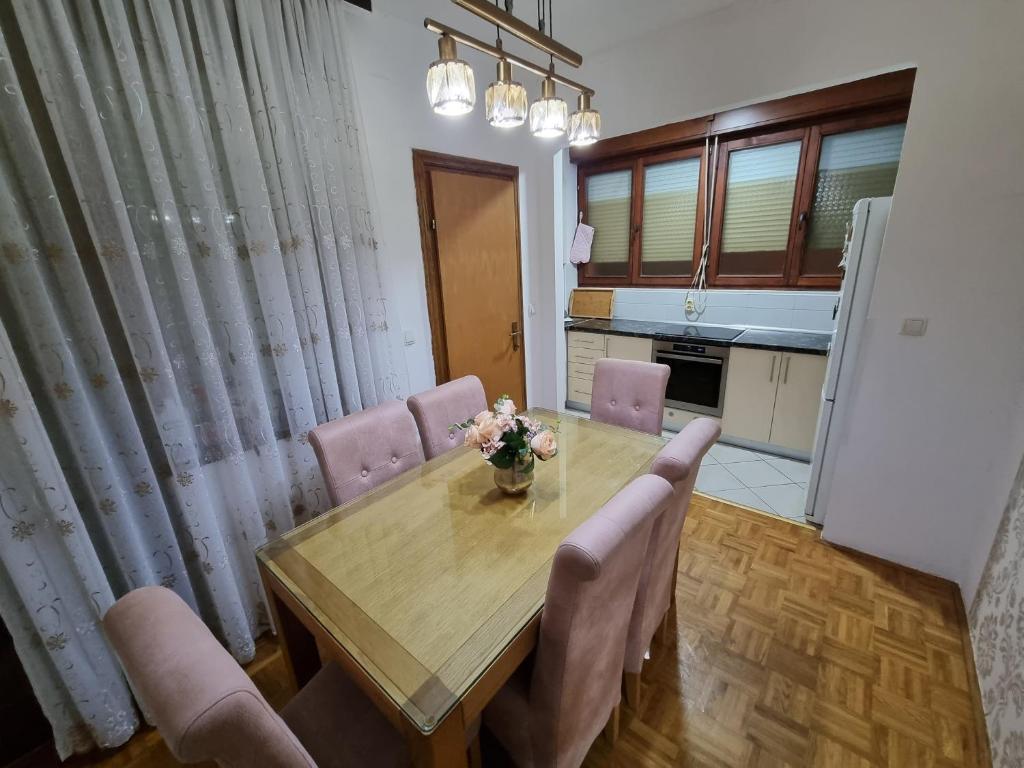 a dining room table with chairs and a vase of flowers on it at Apartman Danijela in Vukovar