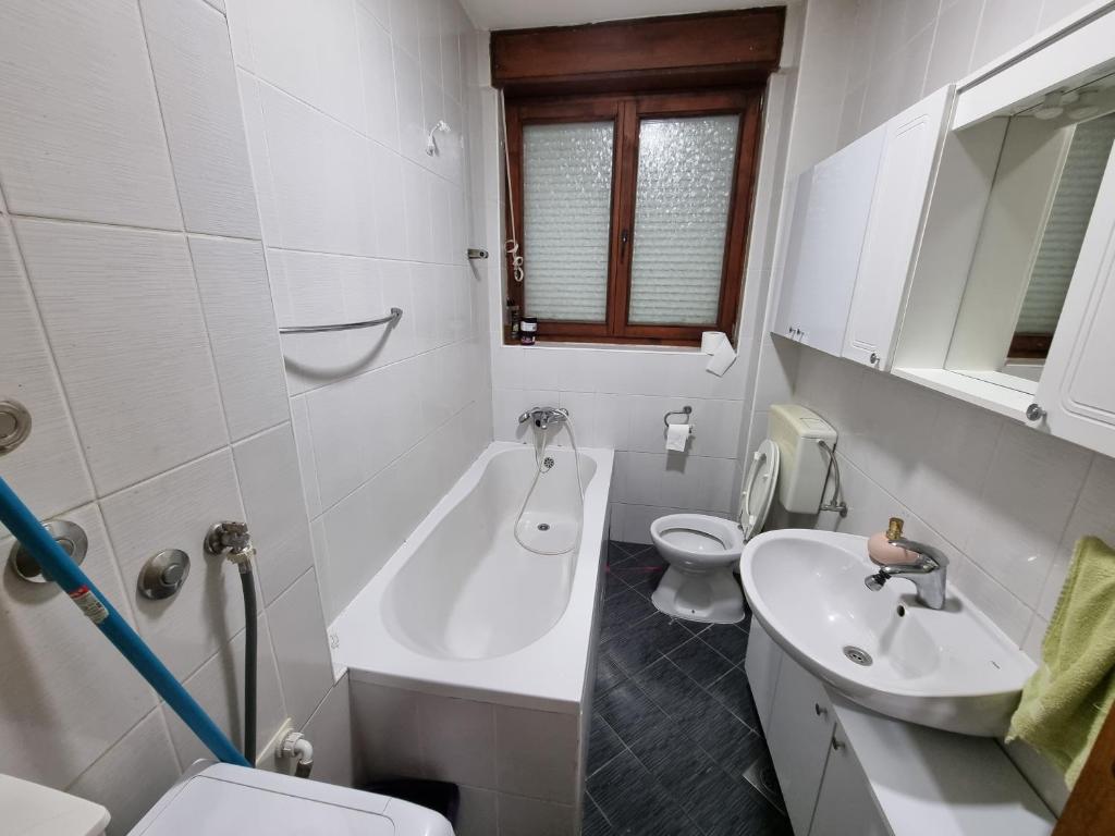 a white bathroom with a sink and a toilet at Apartman Danijela in Vukovar