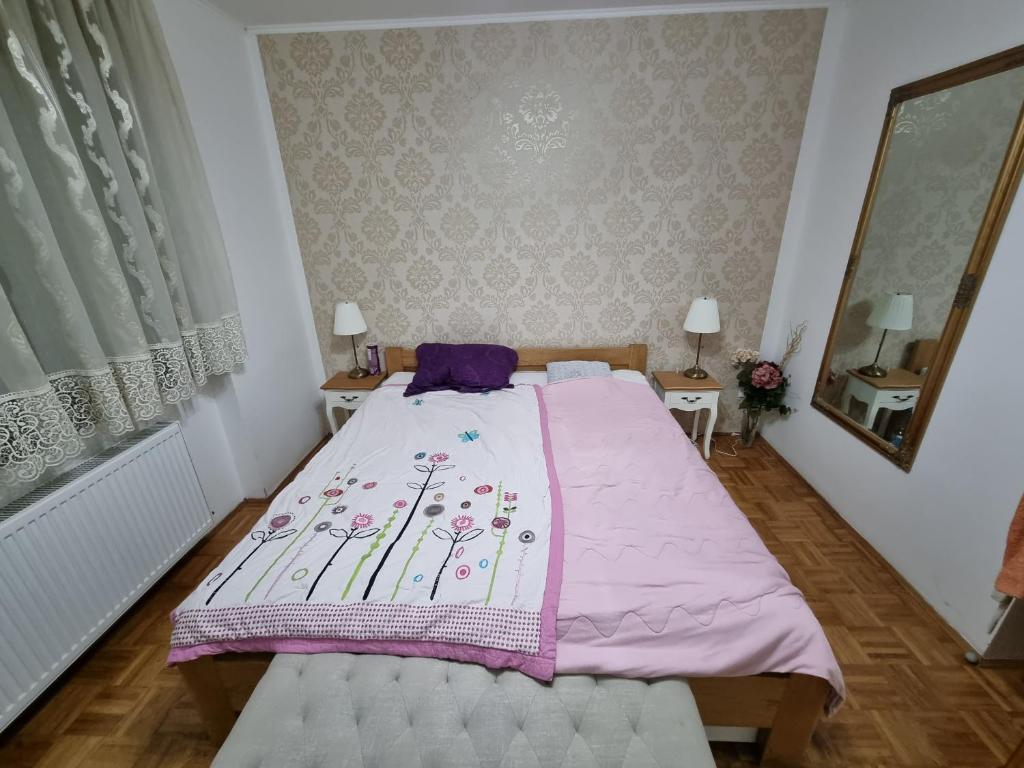 a bedroom with a large bed with a pink blanket at Apartman Danijela in Vukovar