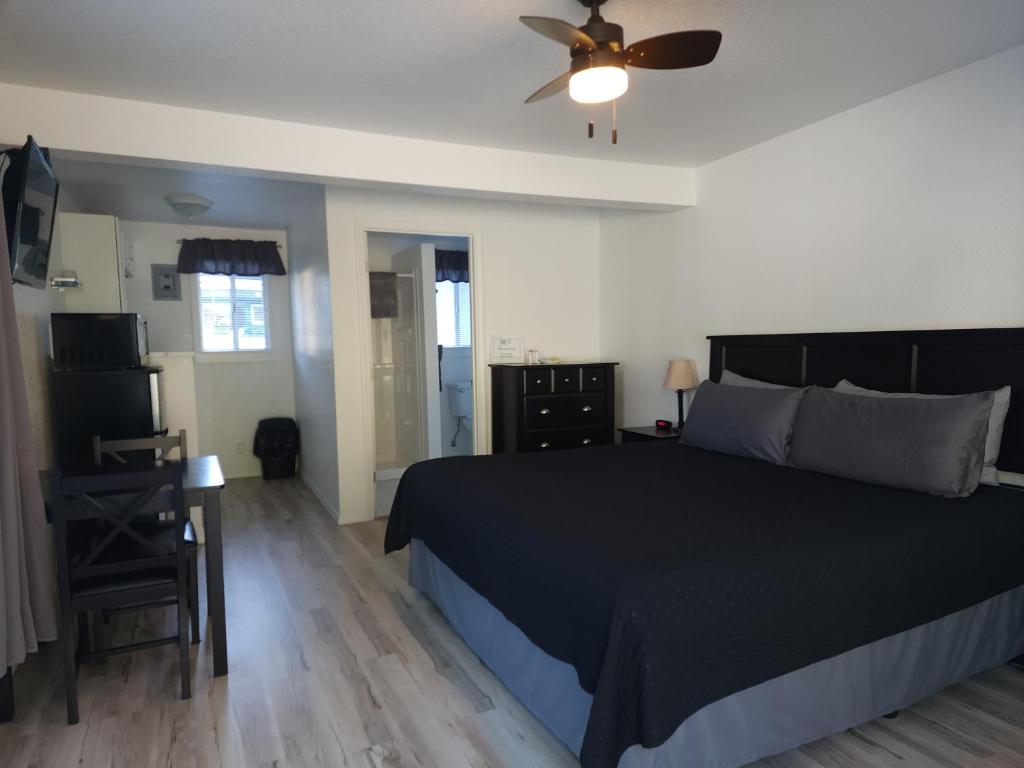 a bedroom with a black bed and a ceiling fan at Plainview Motel in Coos Bay