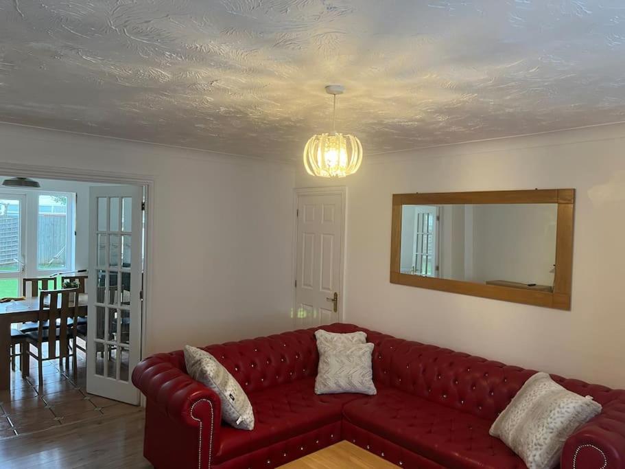 a living room with a red couch and a mirror at Beautiful 4 bedroom home 3 bathrooms, Excellent location, Family, Group, Corporate, Contractor in Thamesmead