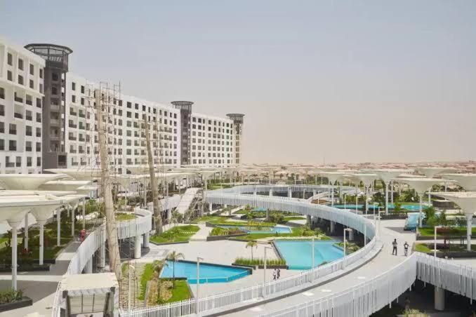 a rendering of a resort with two pools and buildings at luxury apartments in cairo , porto new cairo , nyum in Cairo