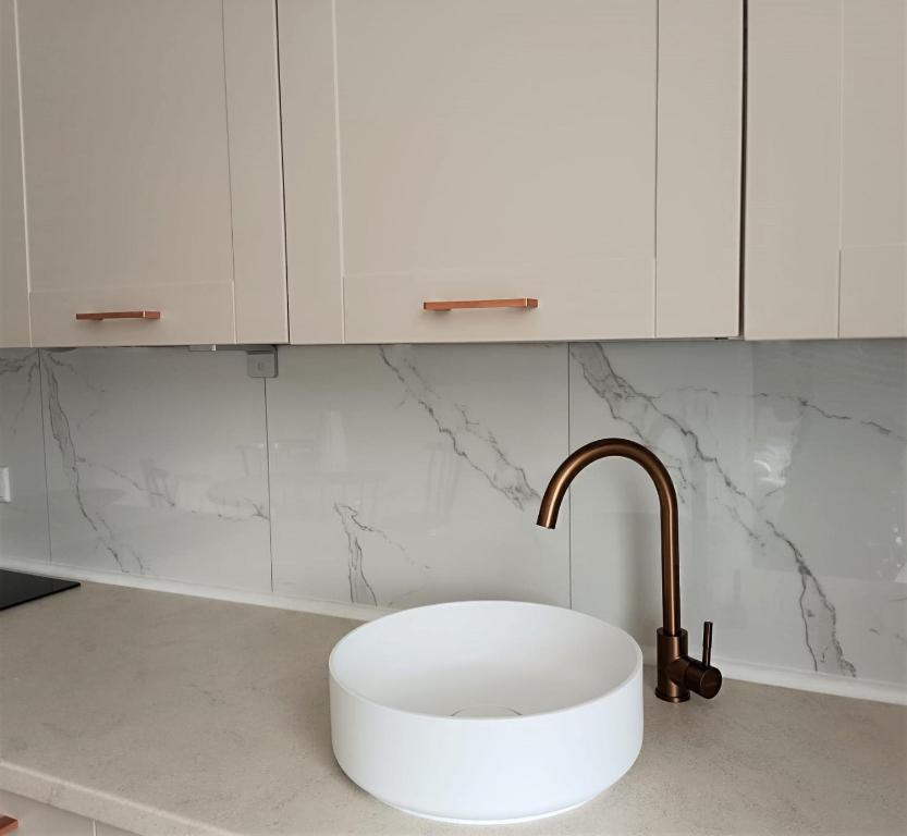 a white kitchen with a sink and a faucet at Gallery Apartment Bielefeld in Bielefeld