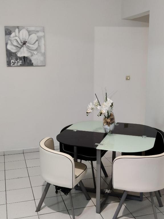 a black table with white chairs and a vase of flowers at HIBISCUS in Baillif