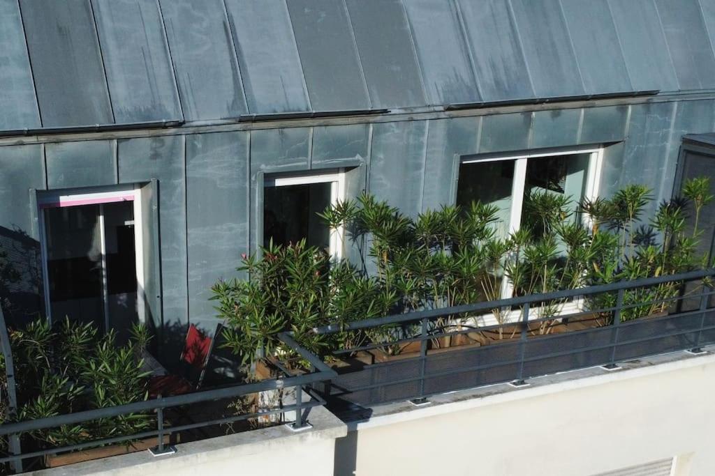 szereg okien z roślinami na budynku w obiekcie Studio avec terrasse proche des transports. w mieście Issy-les-Moulineaux