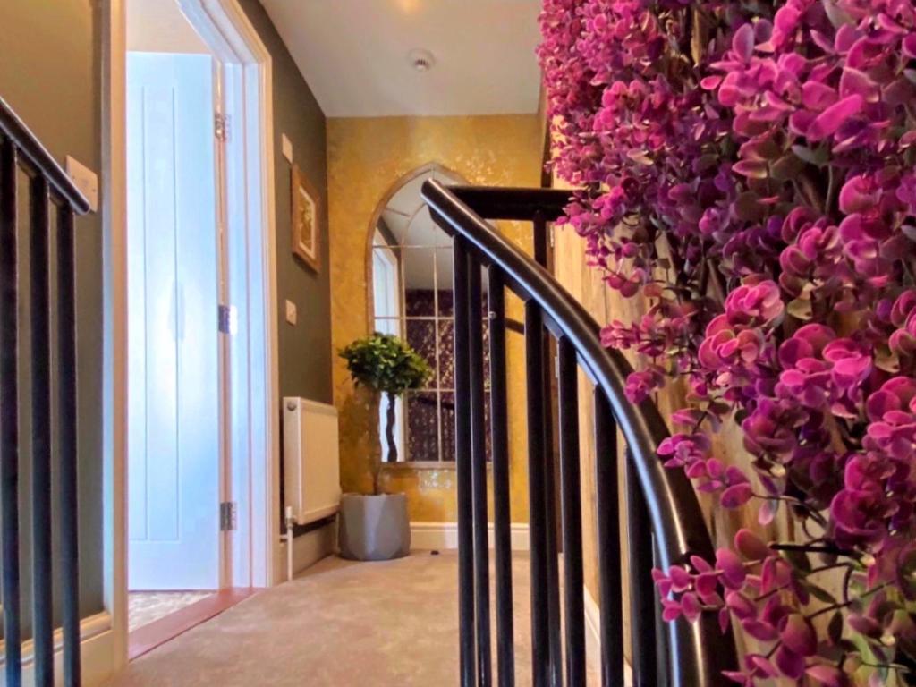 a hallway with a staircase with pink flowers at Luxury tree-house with optional ESPA Spa in Canterbury