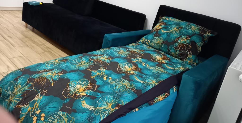 uma cama com um edredão azul e uma almofada em Apartament Różana Piątka em Kutno