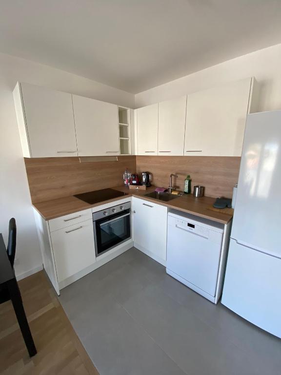 uma pequena cozinha com armários brancos e um lavatório em Luxury appartement 5 Asnières Paris em Asnières-sur-Seine