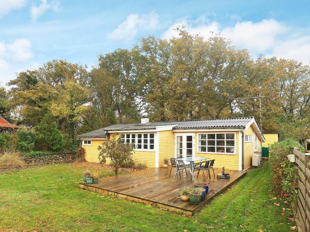 ein kleines gelbes Haus mit einer Terrasse im Hof in der Unterkunft Holiday home Haarby IV in Brunshuse