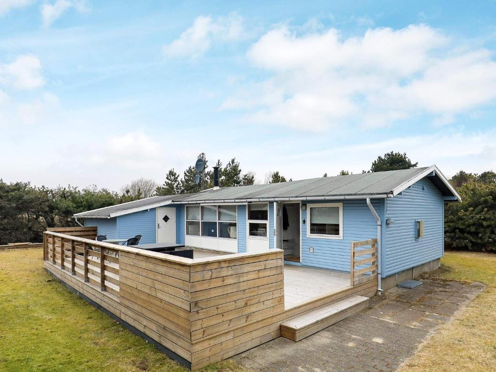 una pequeña casa azul con una gran terraza en 6 person holiday home in S by en Sæby