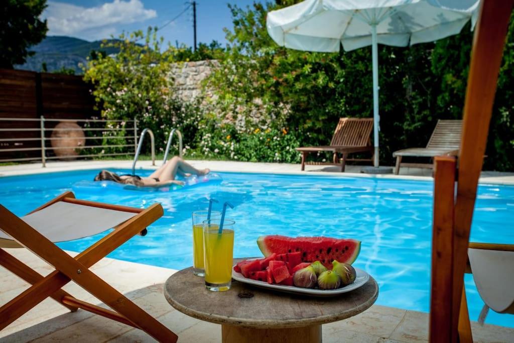 un plato de fruta en una mesa junto a la piscina en Villa Melina with pool by the sea, en Palaia Epidavros