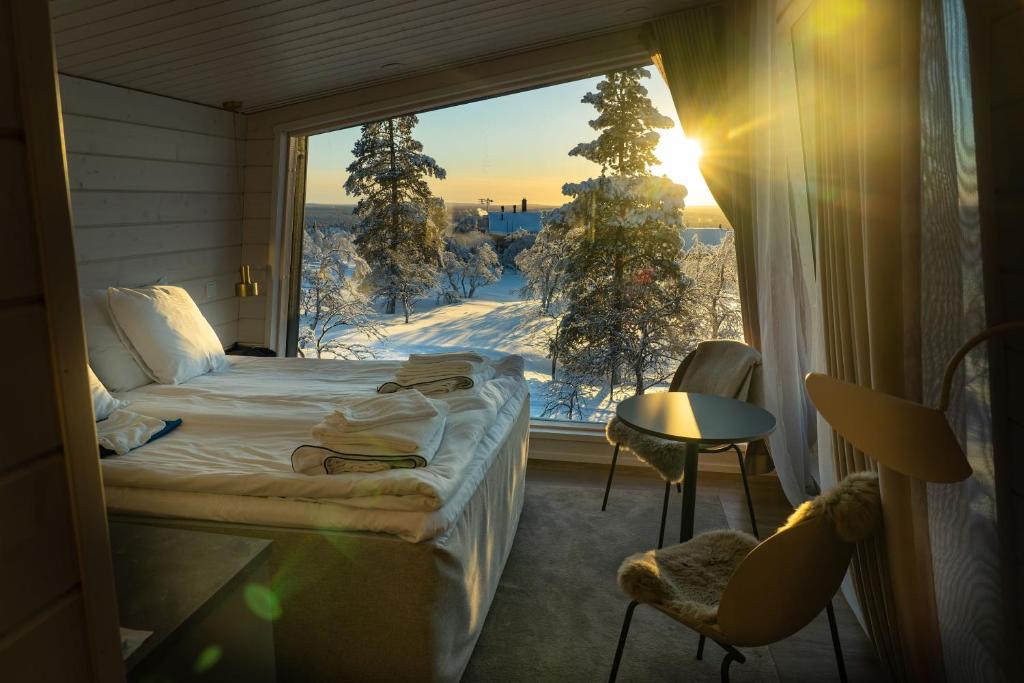 a bedroom with a bed and a window with a snow covered yard at Aurora Collection in Saariselka