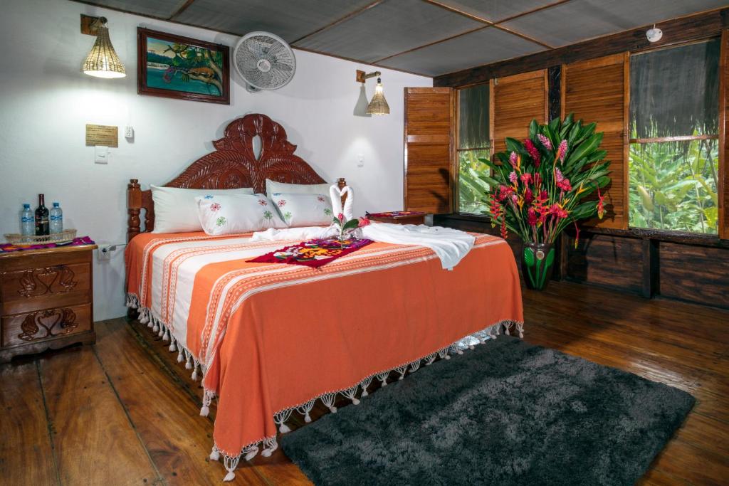 ein Schlafzimmer mit einem Bett mit orangefarbener Tagesdecke und Blumen in der Unterkunft Las Guacamayas Lodge Resort, Selva Lacandona, Chiapas México in Tlatizapán