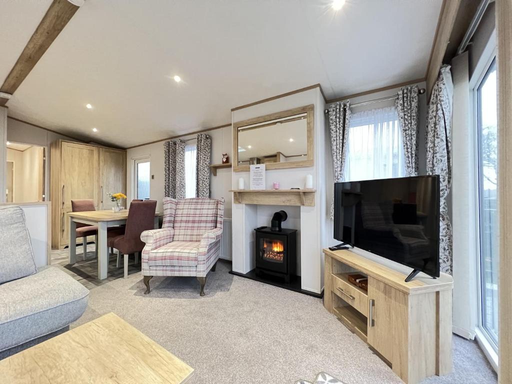 een woonkamer met een flatscreen-tv en een tafel bij Stewarts Resort Lodge 23 in St Andrews