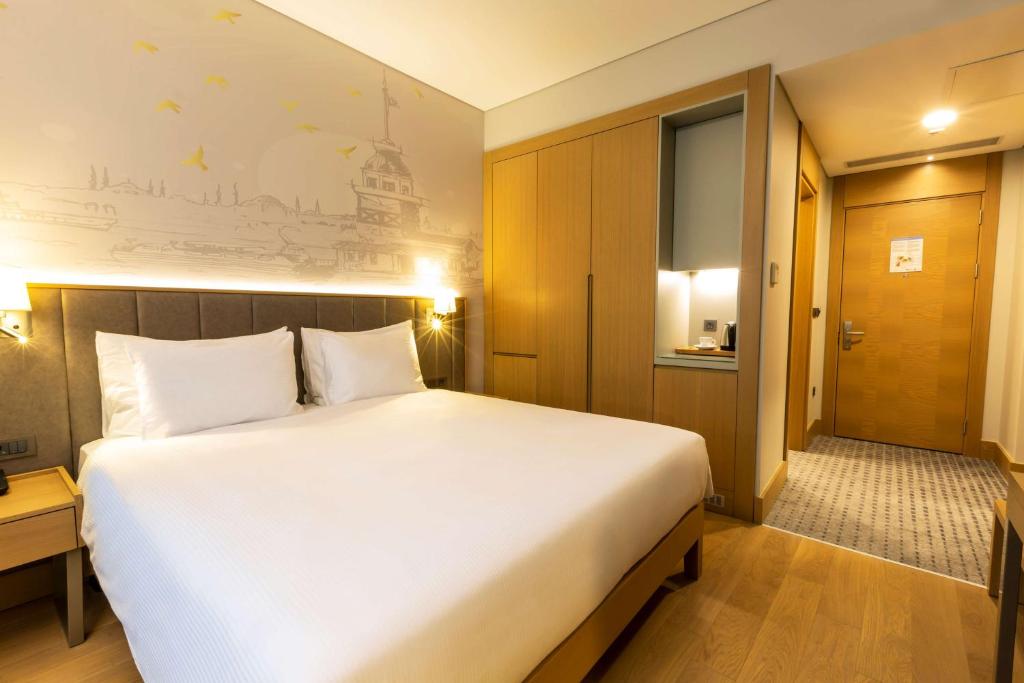 a bedroom with a large white bed and a door at Radisson Hotel Istanbul Harbiye in Istanbul