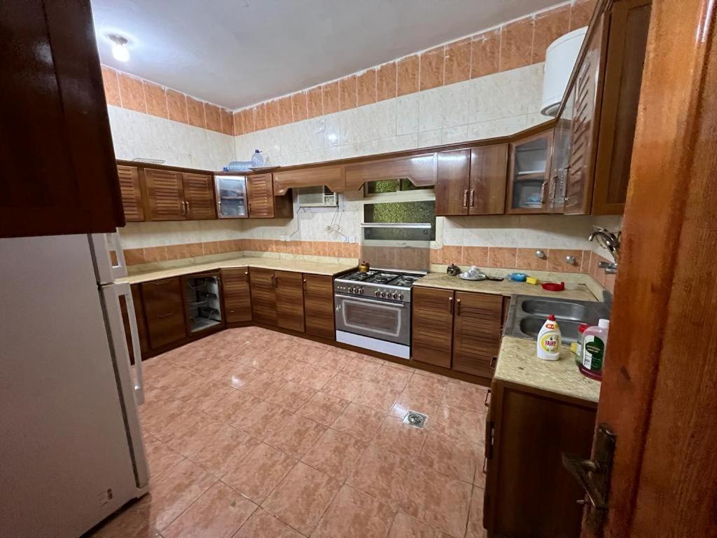 a large kitchen with wooden cabinets and a stove at Albashier private apartment in AlUla