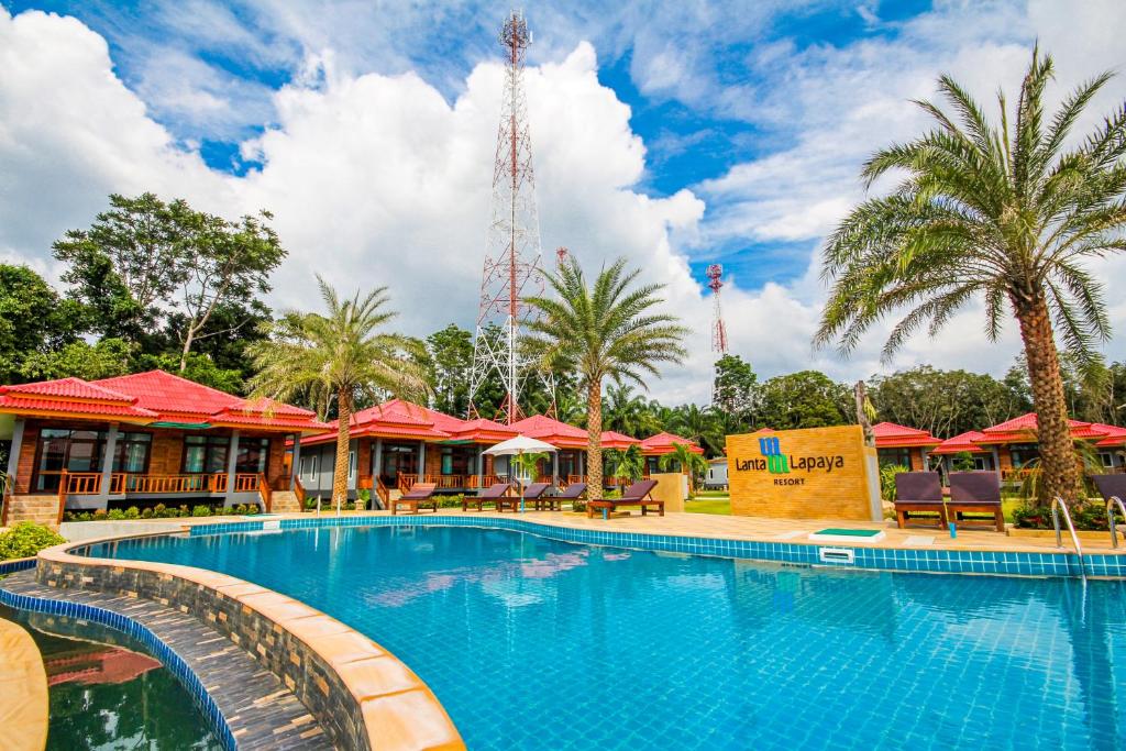 une piscine dans un complexe avec des palmiers et des parasols rouges dans l'établissement Lanta Lapaya Resort, à Ko Lanta