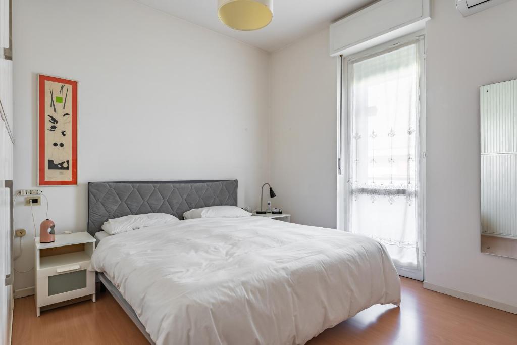 a white bedroom with a large bed and a window at Attico Montiglio - by Host4U in Brescia