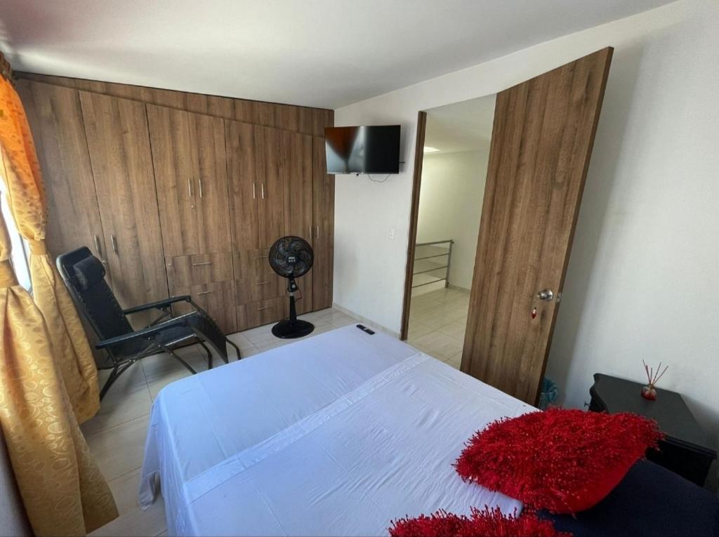 a bedroom with a white bed with a red pillow on it at Habitación en casa in Pereira