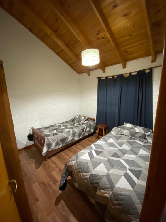 two beds in a room with blue curtains at Cabaña Lucio in Esquel