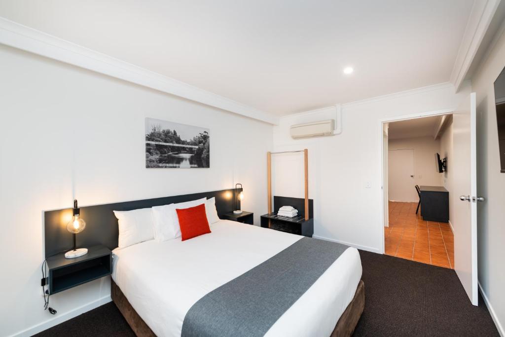 a hotel room with a large bed and a hallway at River Motel in Queanbeyan