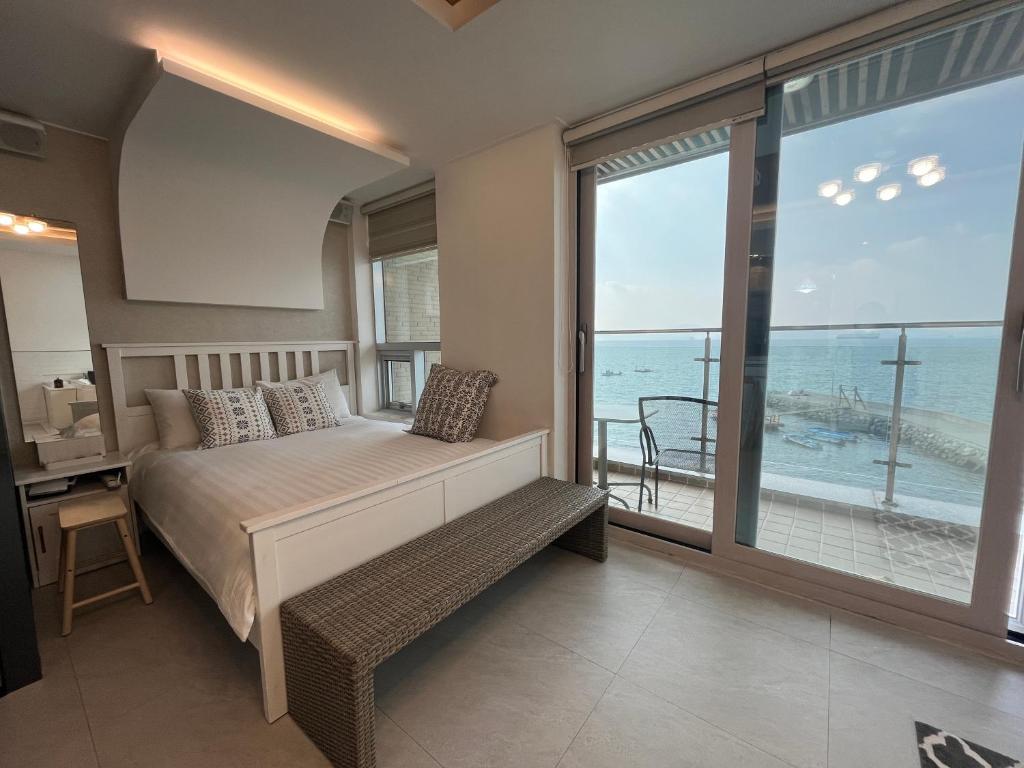 1 dormitorio con cama y vistas al océano en Somewhales Pension, en Namhae