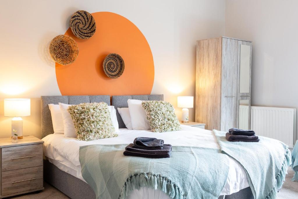 a bedroom with a bed with an orange headboard at Logan House, Modern and Spacious Townhouse close to City Centre in Carlisle
