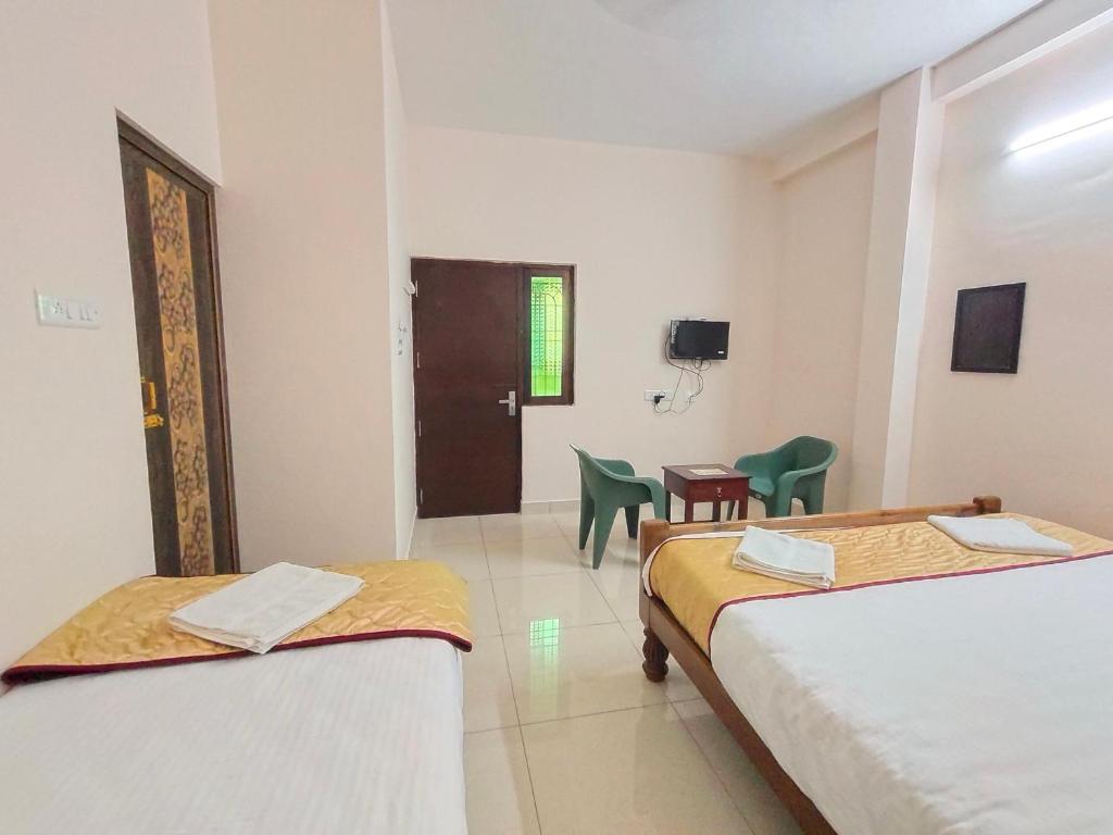 Cette chambre comprend deux lits, une table et des chaises. dans l'établissement La Township Residency, à Pondichéry