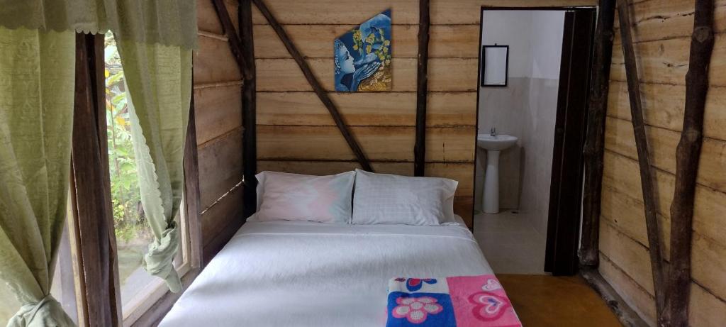 uma pequena cama num quarto com uma janela em Sapiens house "cabaña del lago" em Cali