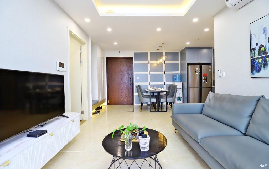 een woonkamer met een blauwe bank en een tafel bij QMP - Vinhomes D'Capitale in Hanoi