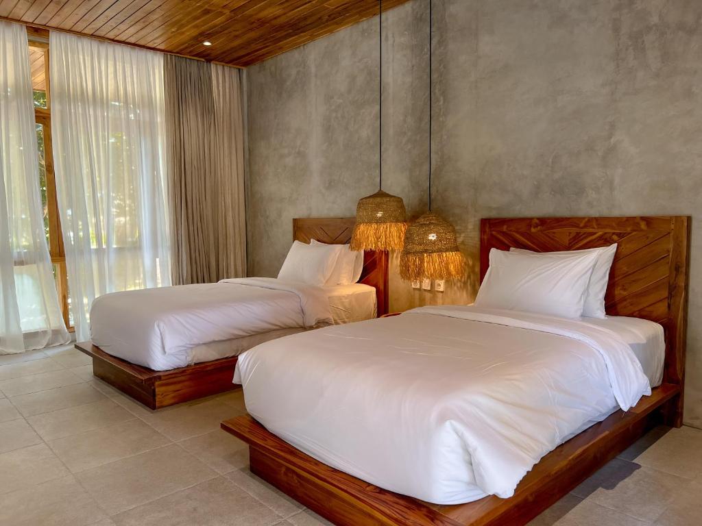 a bedroom with two beds with white sheets at Diamond Beach Villas in Nusa Penida