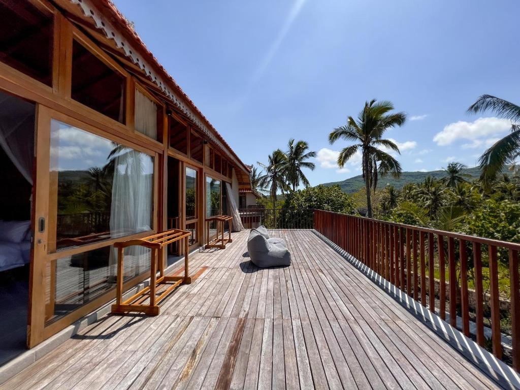 a wooden deck on a house with palm trees at Diamond Beach Villas in Nusa Penida