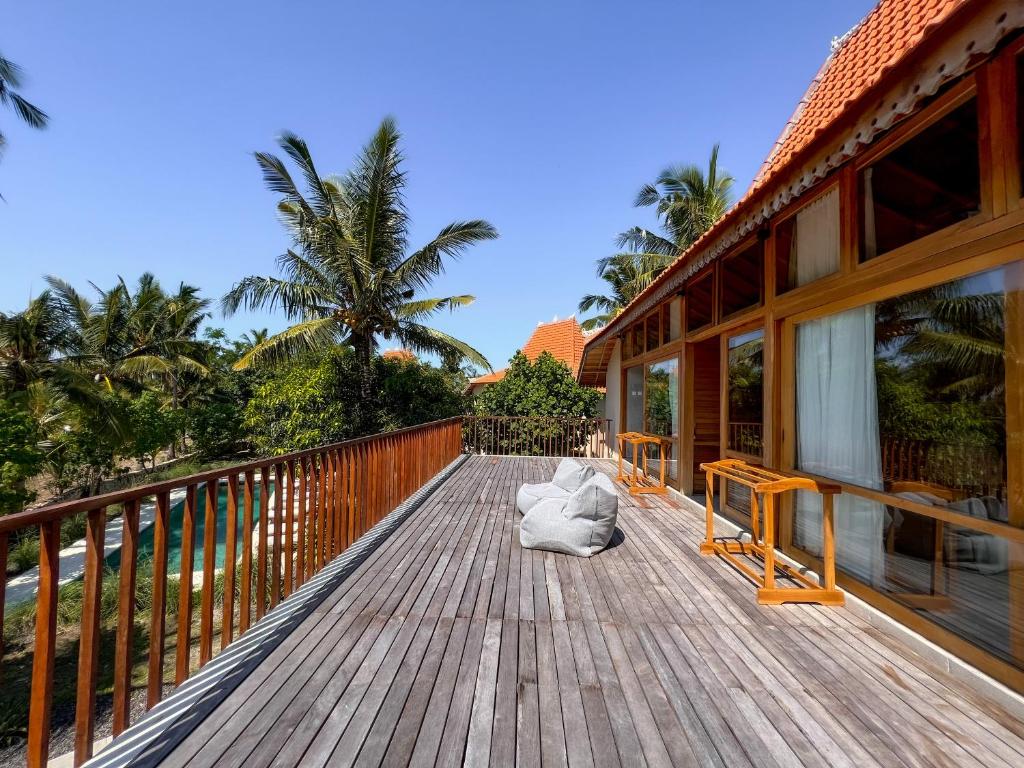 a wooden deck of a house with palm trees at Diamond Beach Villas in Nusa Penida