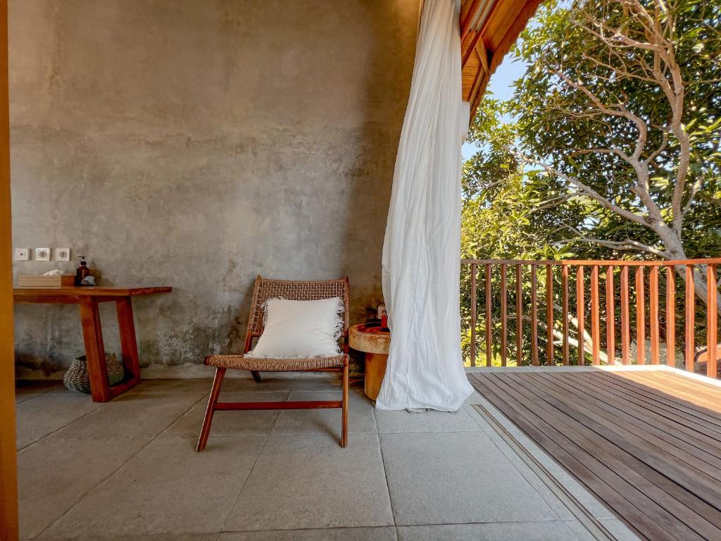 a chair on a porch with a table and a window at Diamond Beach Villas in Nusa Penida
