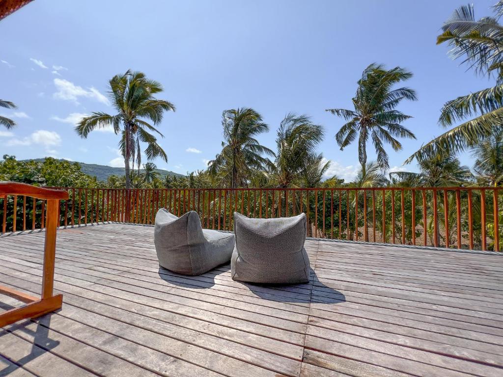 two chairs sitting on a wooden deck with palm trees at Diamond Beach Villas in Nusa Penida