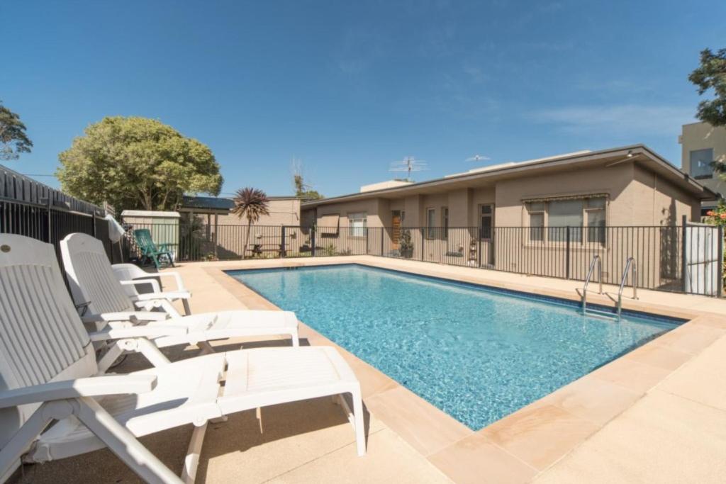a swimming pool with lounge chairs next to a house at On The Beach in Rosebud