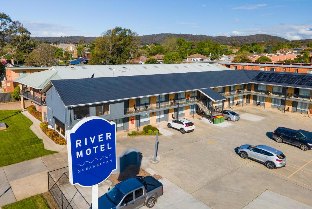 une vue de tête sur un hôtel avec un panneau dans un parking dans l'établissement River Motel, à Queanbeyan