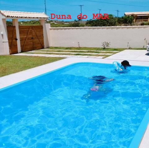 アラルアマにあるCasarão de Praia com Piscinaの青いプールでフリスビーで遊んでいる人