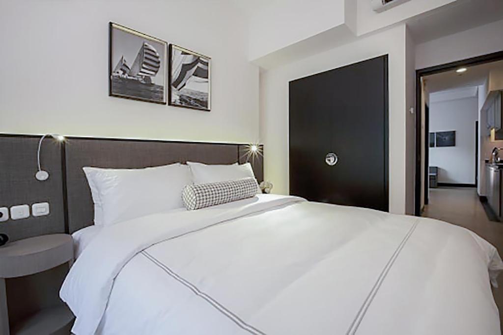 雅加達的住宿－Lemansion Senopati，一间卧室配有一张白色大床和黑色床头板