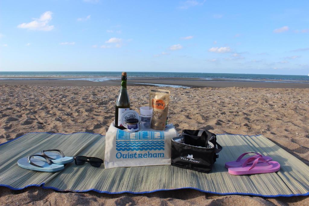 a bottle of wine and glasses on a blanket on the beach at La Villa Andry in Ouistreham