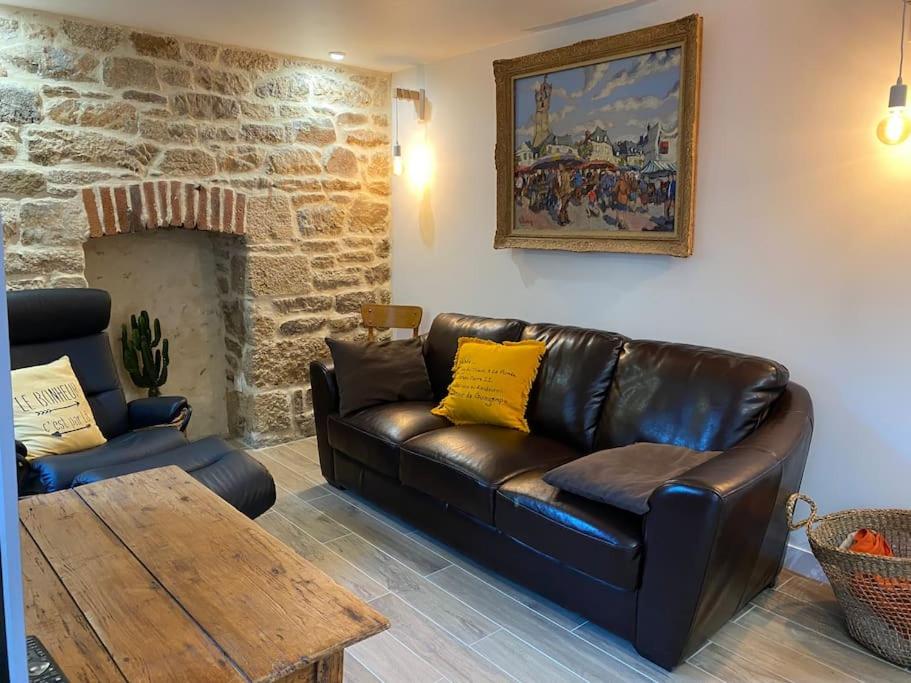 a living room with a leather couch and a table at Studio cosy tout équipé en cœur de ville au calme in Guingamp